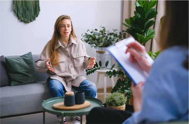 a person with a notepad sitting across from a woman on the couch