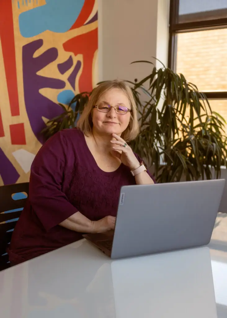 Janet cook sitting at desk with Laptop in front of her open.